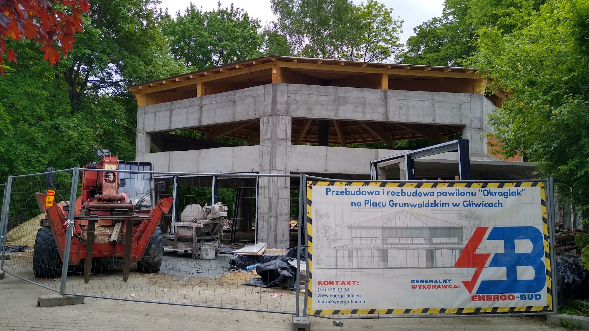 Fot. M.Foltyn/UM Gliwice budynek Okrąglaka wśród zieleni. Na płocie baner z wizualizacją obiektu