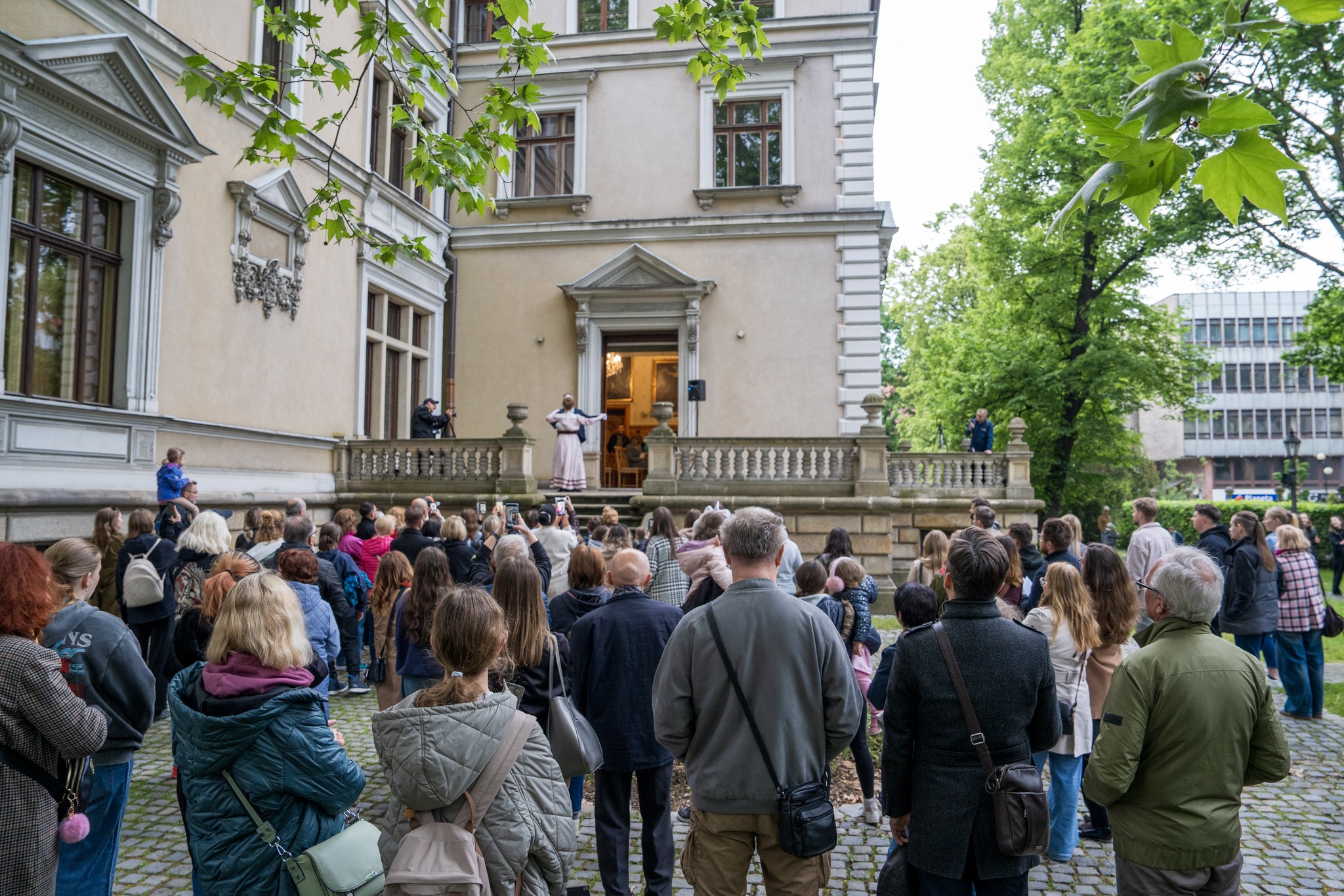 ludzie prezd Willą Caro, patrzą jak para tańczy na tarasie