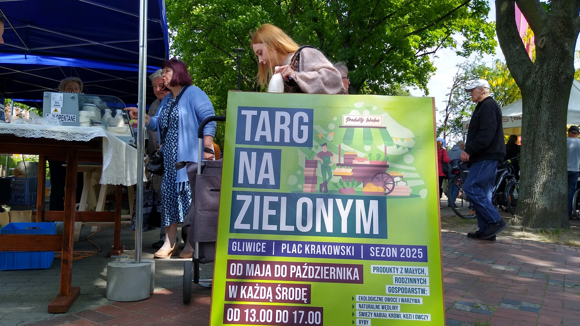 tablica z informacją o godzinach działania targu i ludzie