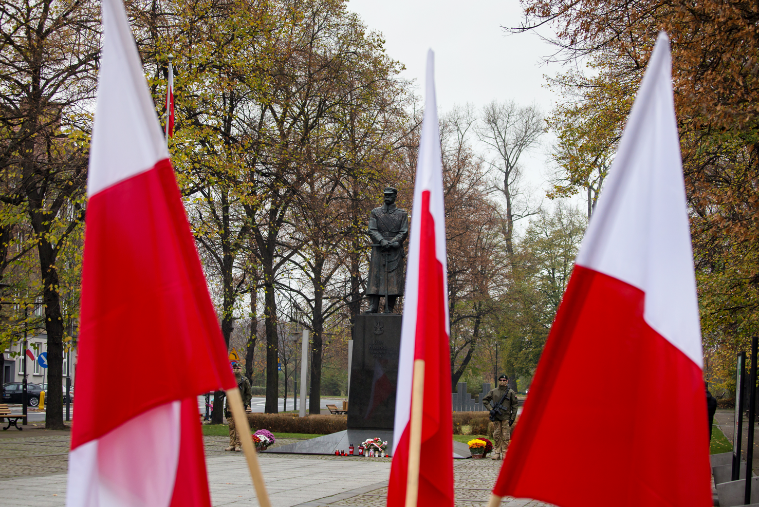 Pomnik marszałka Józefa Piłsudskiego widoczny zza polskich flag