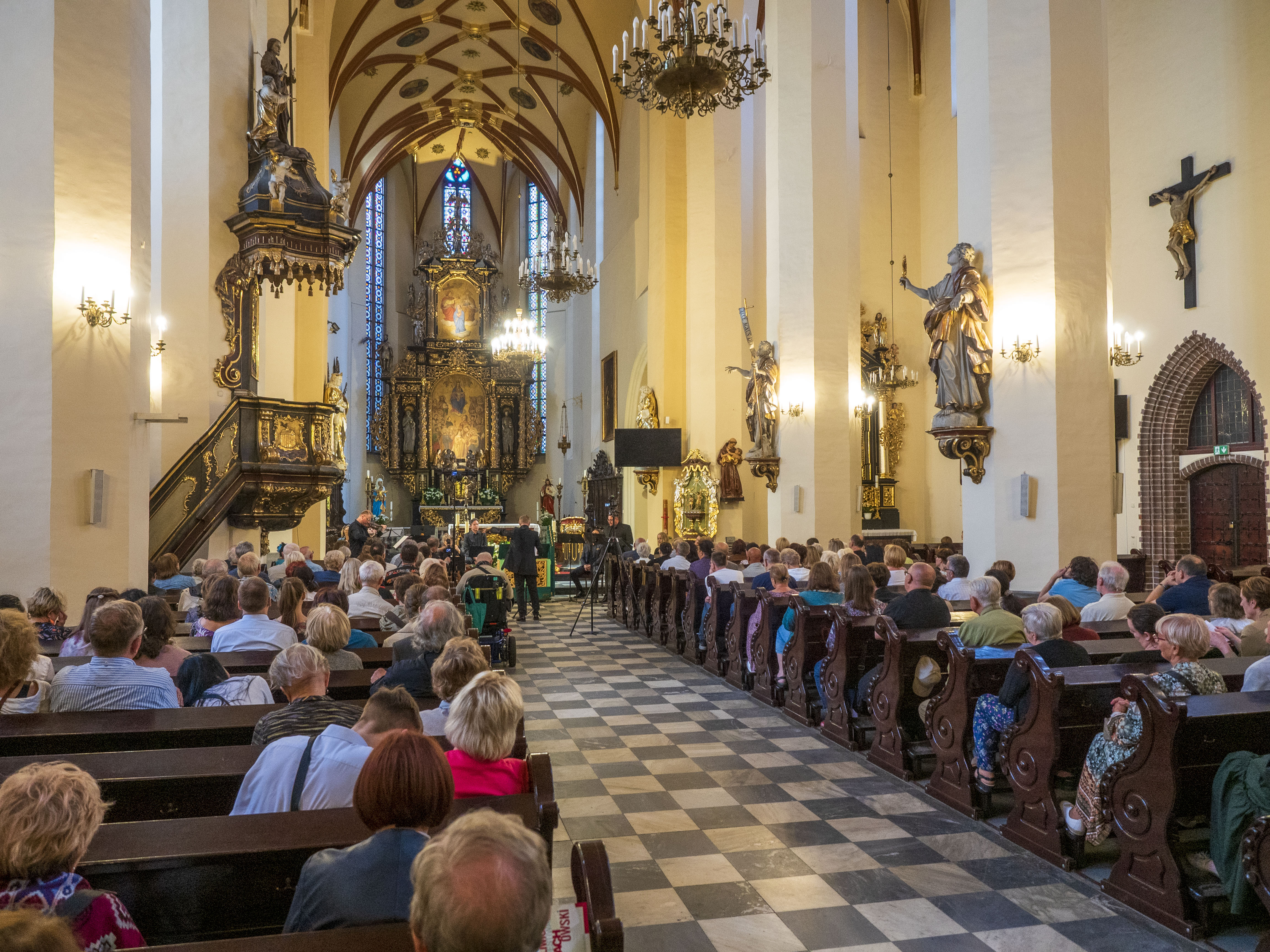 publiczność słuchająca koncertu w kościelnych ławach