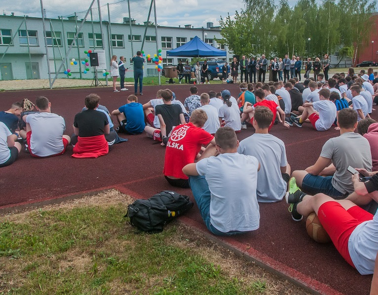 uczniowie siedzą na boisku