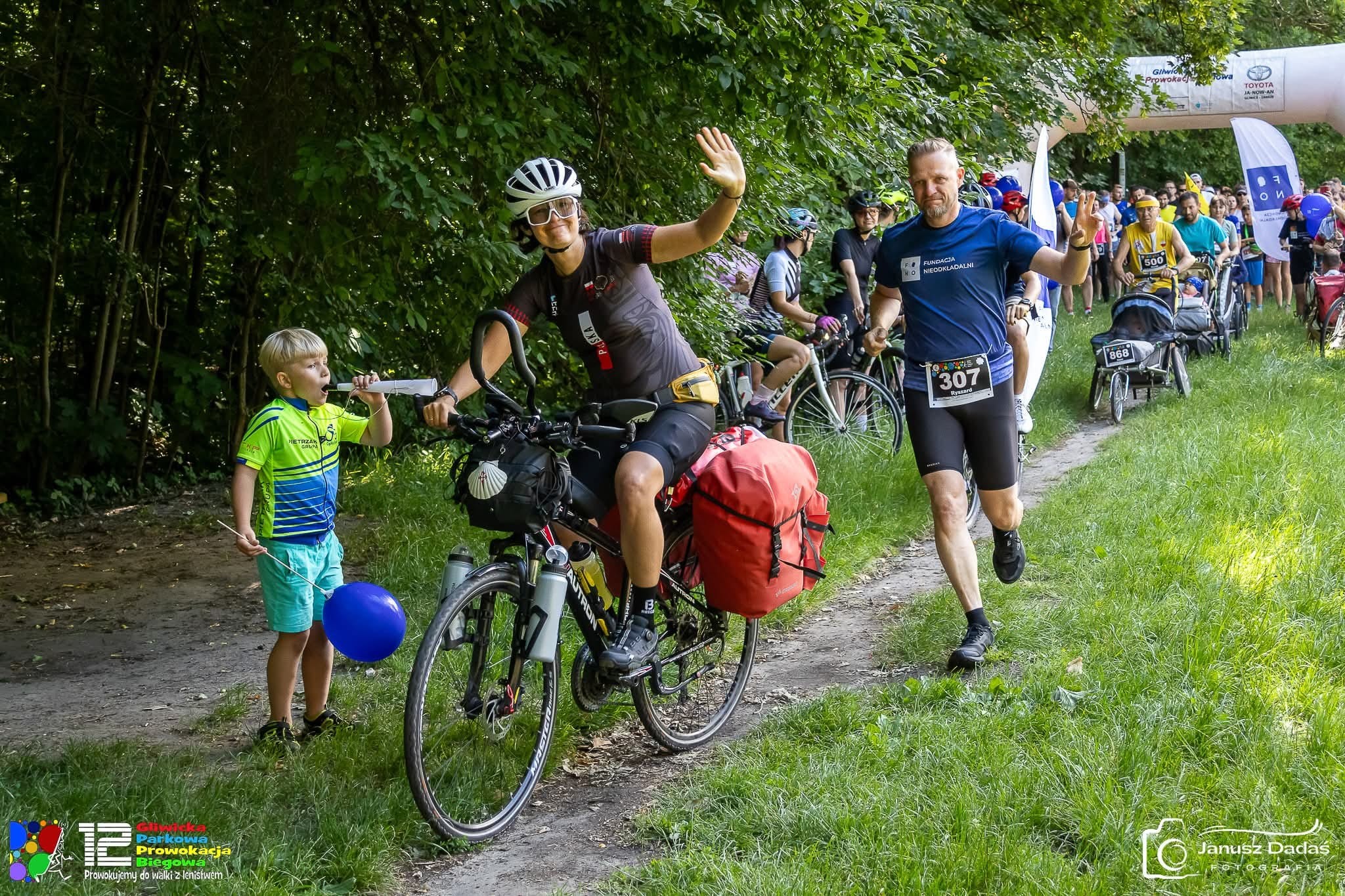 kobieta na rowerze, dziecko z trąbką, mężczyzna biegnie