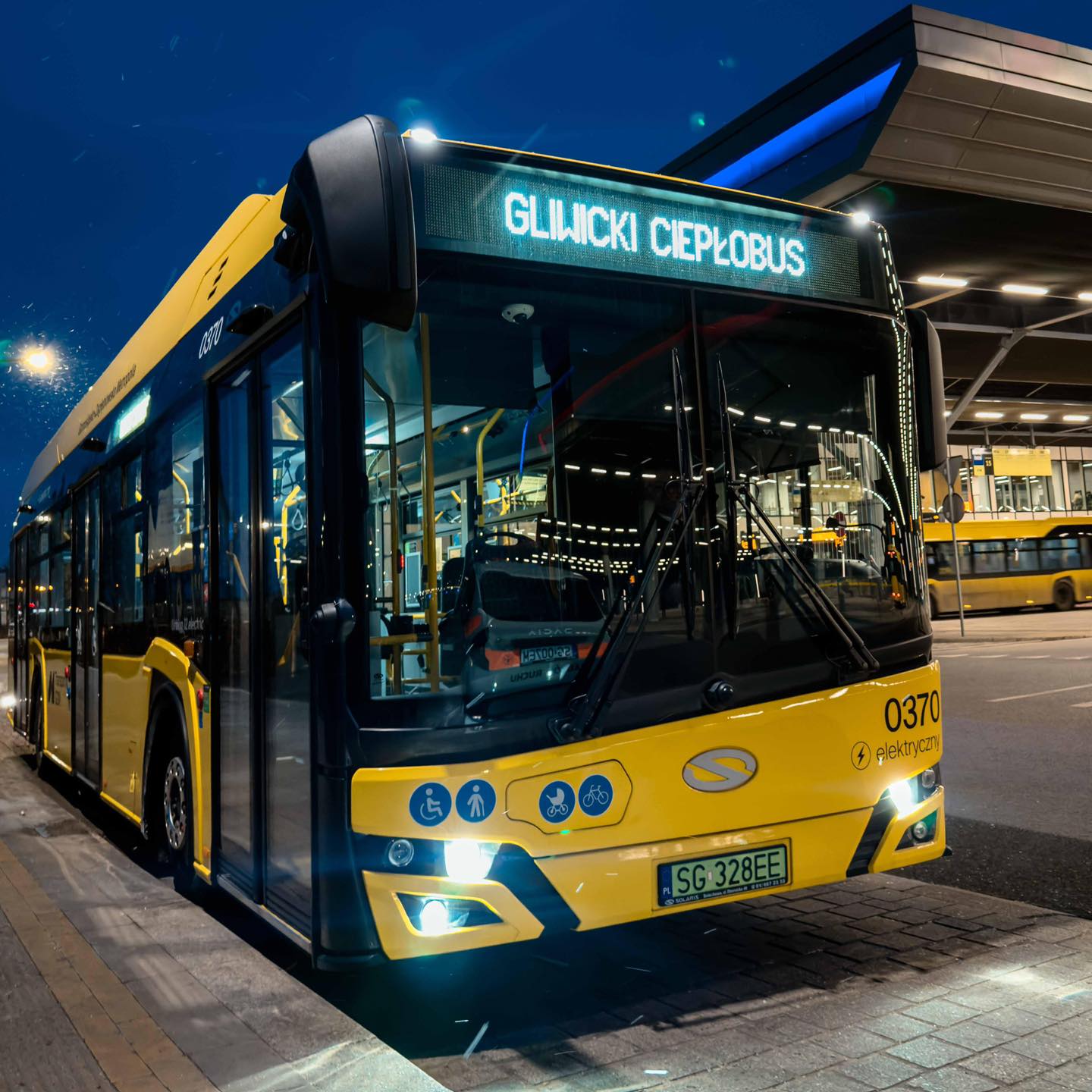 stojący żółty autobus, Centrum Przesiadkowe w tle